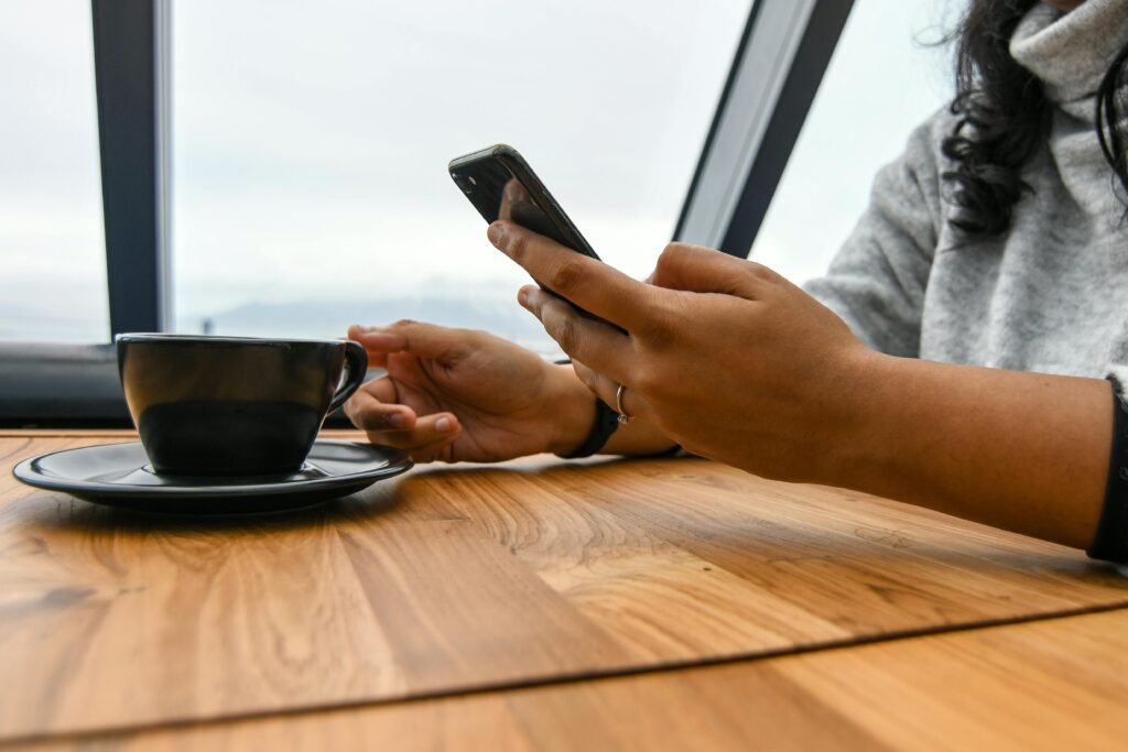 pexels-photo-1047254-1047254 A woman enjoys coffee while browsing her smartphone in a modern café setting.