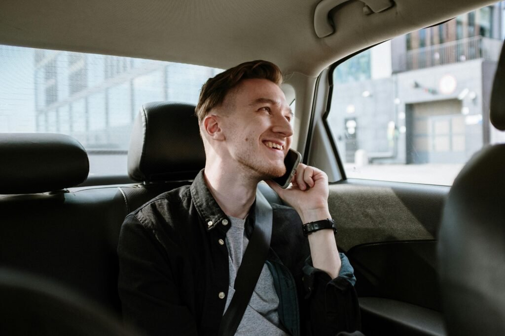pexels-photo-4606338-4606338 Smiling young man enjoying a phone call while seated in the back seat of a car during a daytime ride.